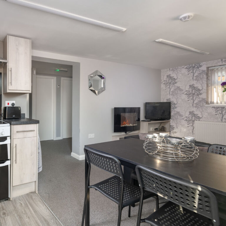 Sleek white modern kitchen and dining area with a black table and grey-toned decor.