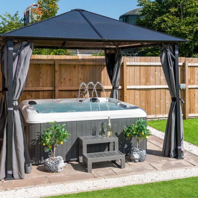 A luxury hot tub under a gazebo on a paved patio at Four Oaks Cottage.