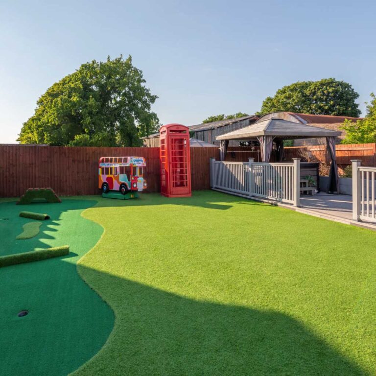 Artificial grass garden with a red telephone box, mini-golf, and a play bus.