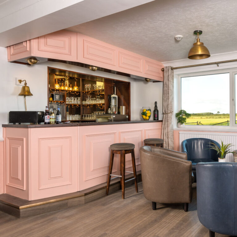 A boutique-style pink private bar with stools and a window view at the Big Pink House.