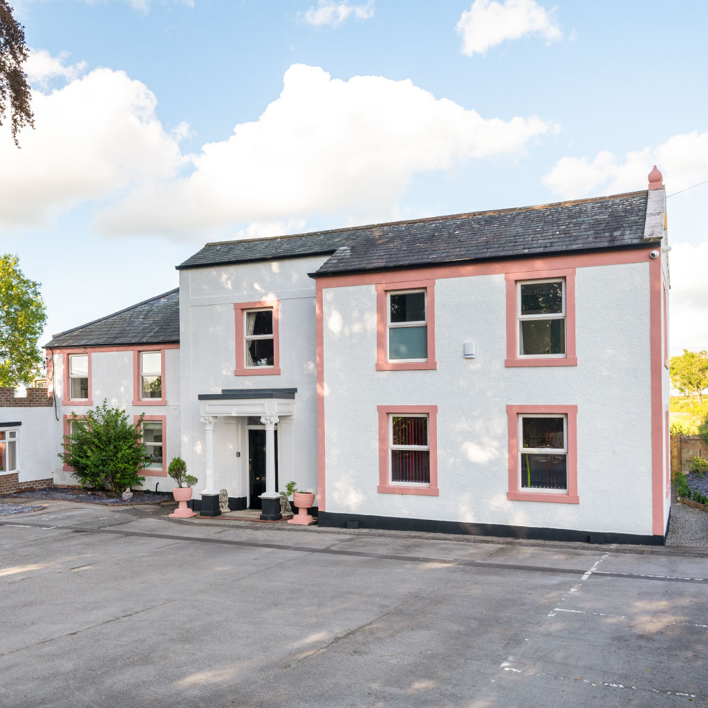 The front exterior of the Big Pink House featuring its signature white and pink colour scheme.