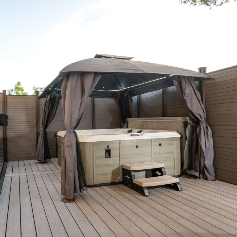 A modern hot tub under a gazebo on a grey deck at the Big Pink House.
