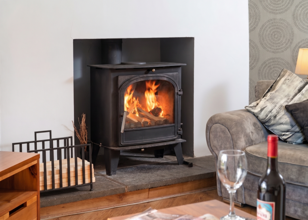 Traditional black wood-burning stove with a bright fire inside at Four Oaks Cottage.