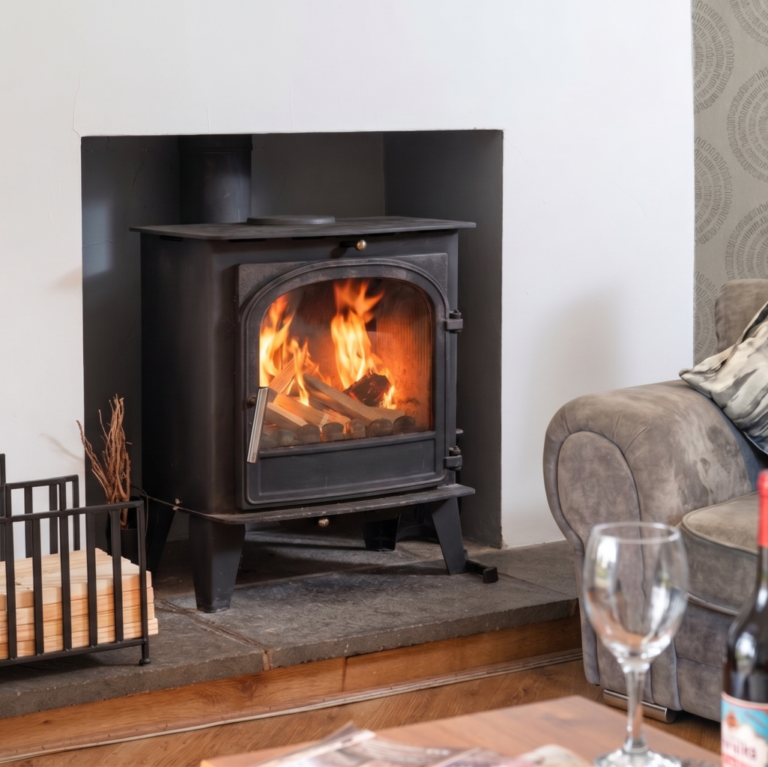 Traditional black wood-burning stove with a bright fire inside at Four Oaks Cottage.